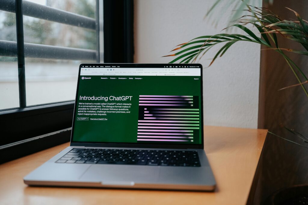 A laptop displaying ChatGPT on a desk by a window, featuring a modern home office setup.