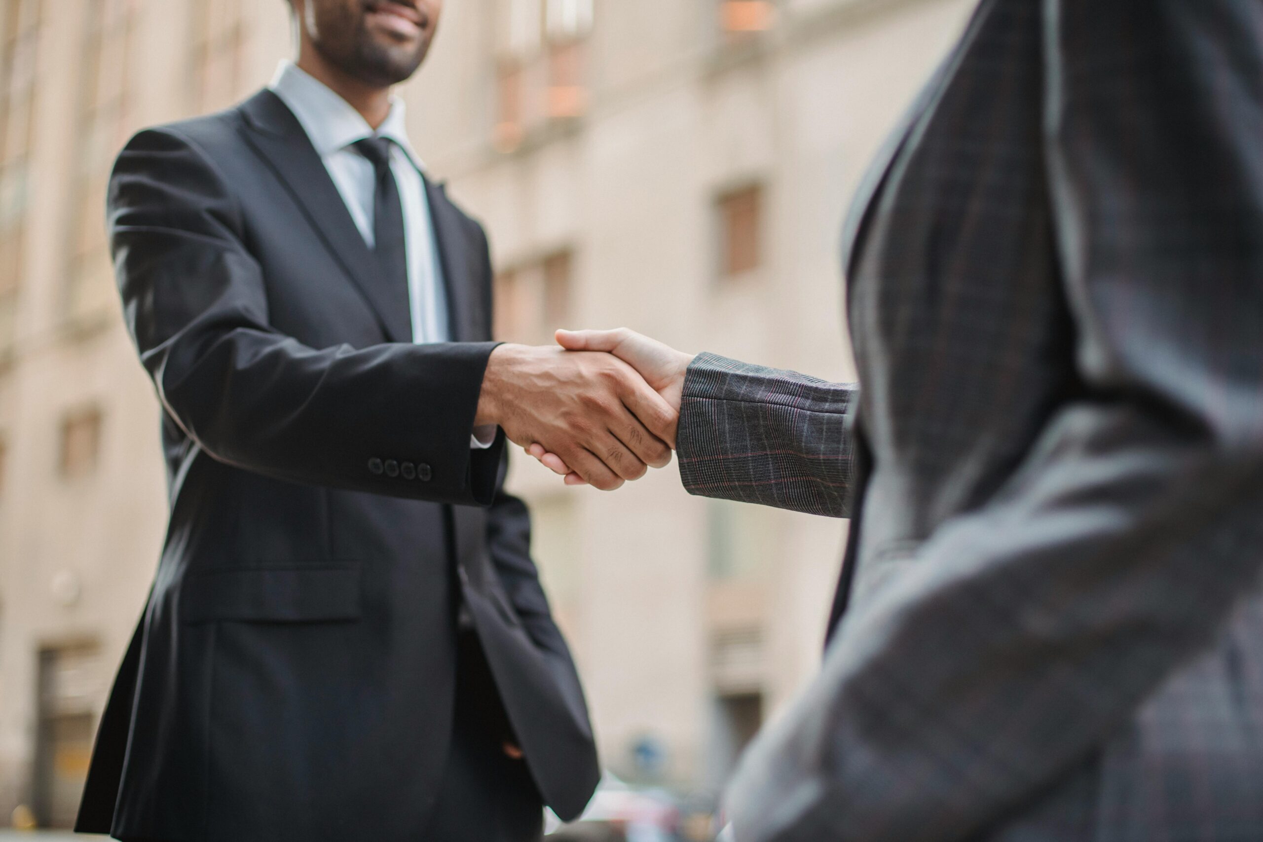 Business professionals greeting each other with a handshake outdoors, symbolizing partnership.