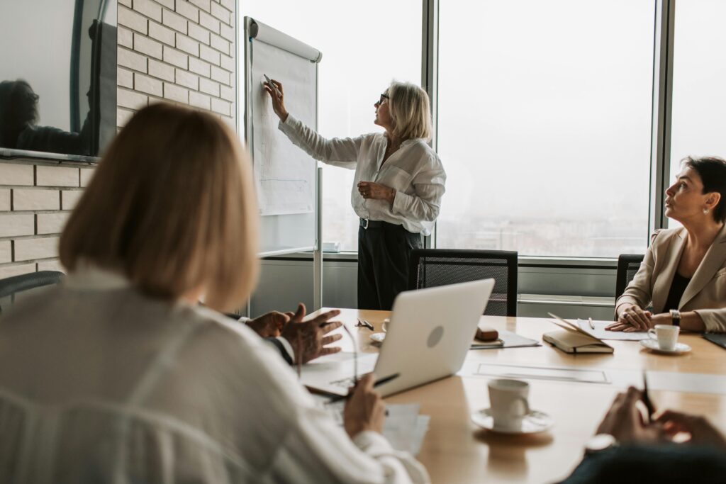 Executive presenting strategy on whiteboard during office meeting.