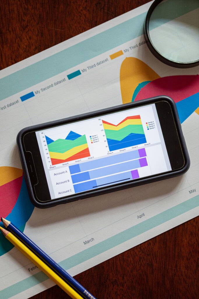 Smartphone displaying colorful data charts and graphs on a paper report with pencils.